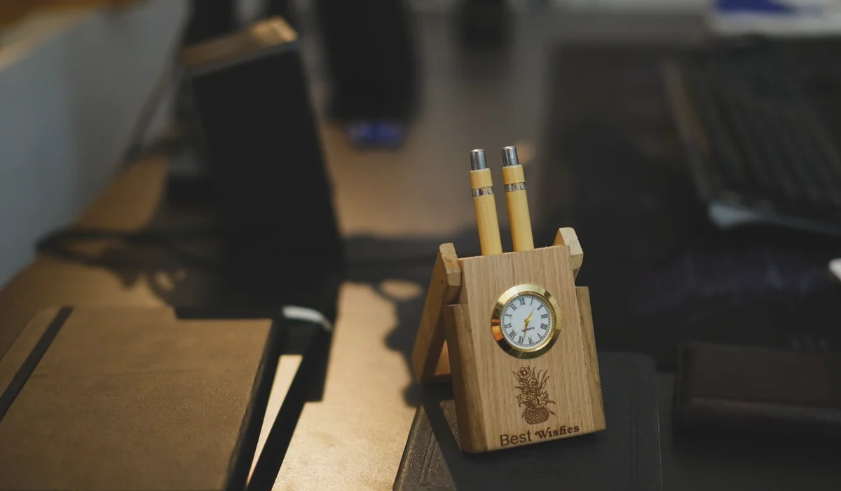 Stylish wooden desk organizer with built-in clock and pens on a modern office desk.